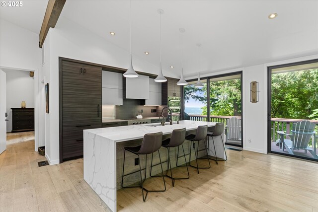 1801 NW Walmer Dr, Portland, OR 97229 - kitchen with modern cabinets, a kitchen island with sink, plenty of natural light, a kitchen bar, and recessed lighting