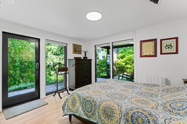 1801 NW Walmer Dr, Portland, OR 97229 - bedroom featuring radiator heating unit, multiple windows, access to outside, and light wood-type flooring