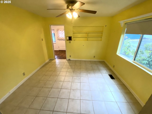 spare room with ceiling fan, light tile patterned floors, and built in shelves