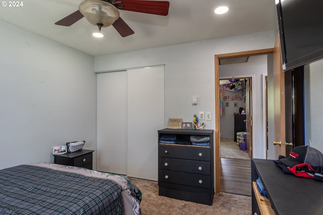 bedroom featuring ceiling fan, a closet, and light colored carpet