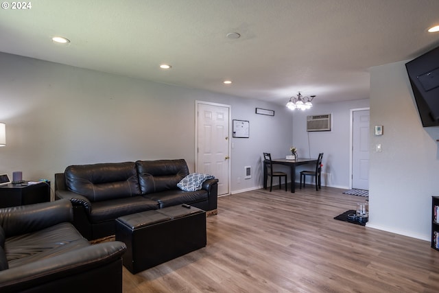 living room with hardwood / wood-style flooring, an inviting chandelier, and an AC wall unit