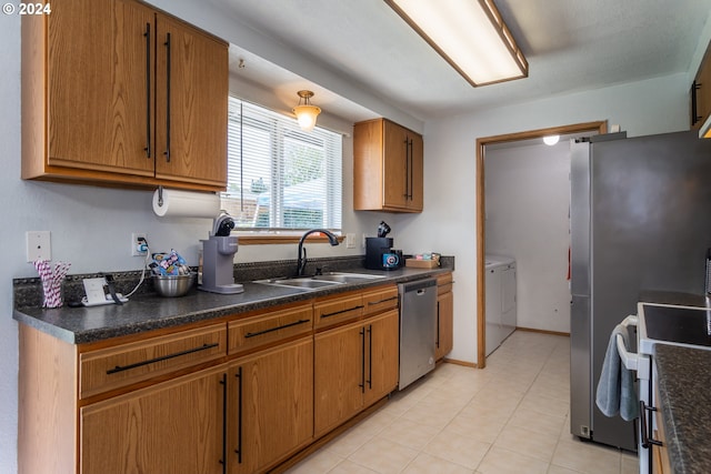 kitchen with independent washer and dryer, range, stainless steel dishwasher, and sink