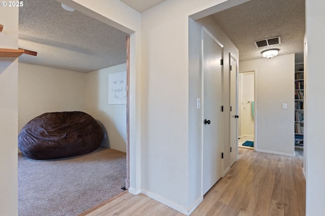 hallway with a textured ceiling and light wood-type flooring