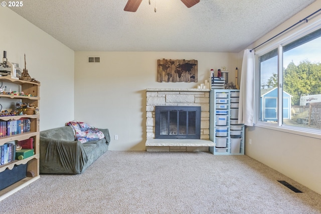 unfurnished living room featuring a stone fireplace, carpet, and a textured ceiling