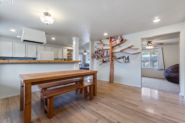 dining area featuring ceiling fan, decorative columns, and light wood-type flooring