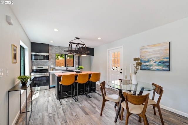dining room featuring light wood finished floors, recessed lighting, and baseboards