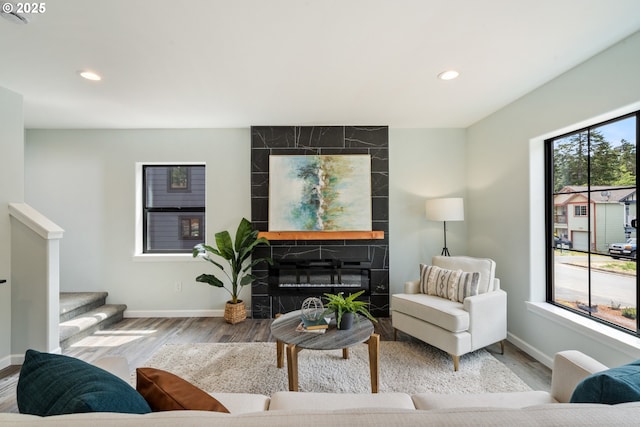 living room featuring baseboards, a tiled fireplace, wood finished floors, recessed lighting, and stairs