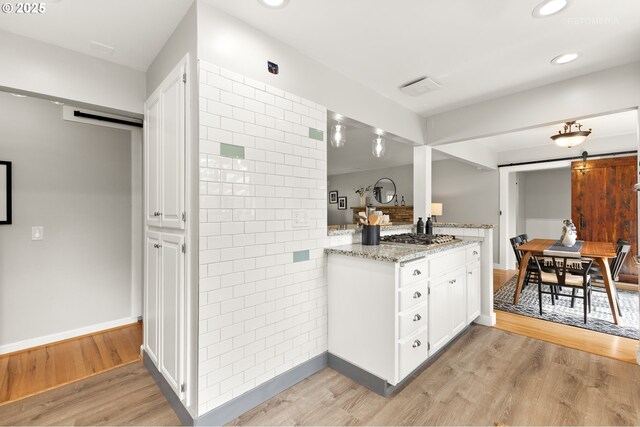 2338 NE 137th Ave, Portland, OR 97230 - kitchen featuring a barn door, light wood finished floors, white cabinetry, light stone counters, and recessed lighting