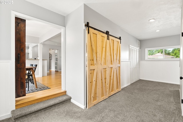 2338 NE 137th Ave, Portland, OR 97230 - hallway featuring carpet floors, a barn door, and a textured ceiling
