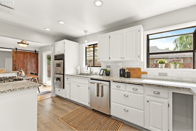 2338 NE 137th Ave, Portland, OR 97230 - kitchen featuring stainless steel appliances, a barn door, recessed lighting, tasteful backsplash, and white cabinetry