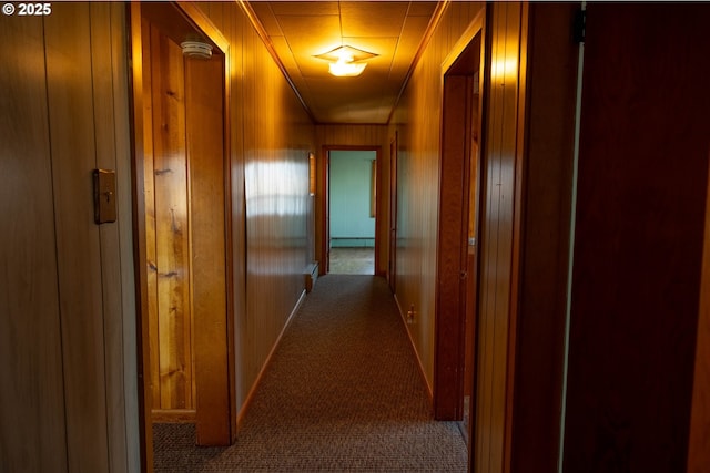 hallway featuring a baseboard radiator, carpet flooring, and wooden walls