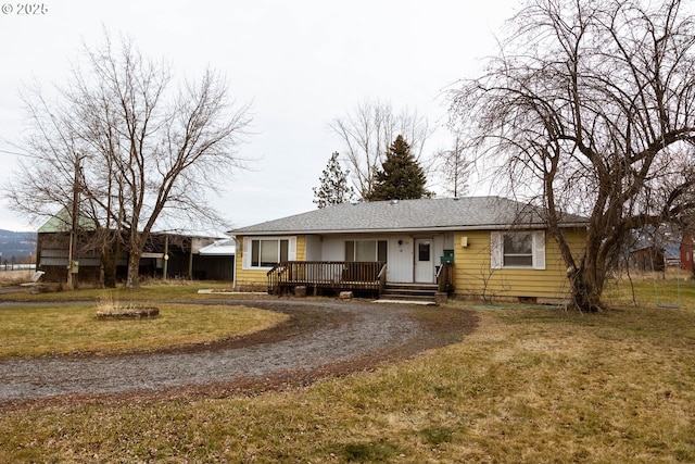 view of front of home featuring driveway, crawl space, roof with shingles, a wooden deck, and a front lawn