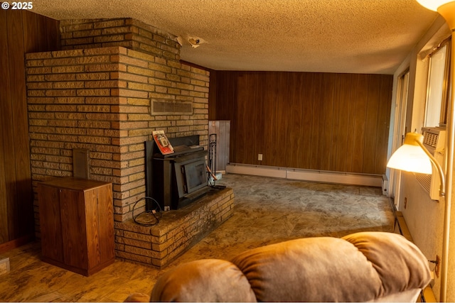 living area with a textured ceiling, baseboard heating, a wood stove, and wooden walls