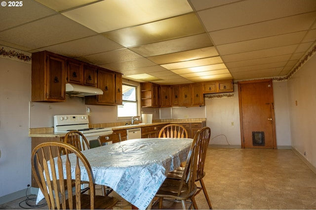 dining area with a paneled ceiling, baseboards, and light floors