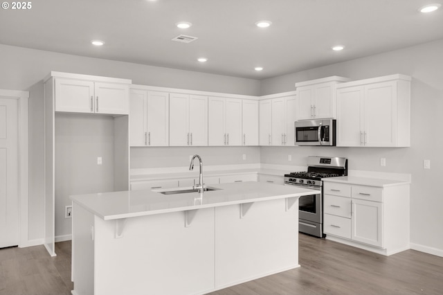 5954 Henshaw St SE, Albany, OR 97322 - kitchen with appliances with stainless steel finishes, a sink, a center island with sink, white cabinetry, and light wood-type flooring