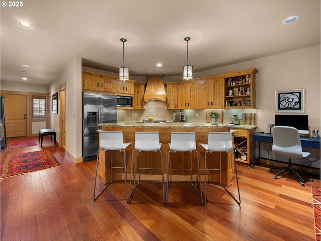 kitchen featuring appliances with stainless steel finishes, open shelves, hardwood / wood-style flooring, premium range hood, and decorative backsplash