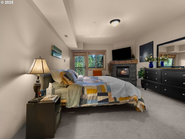 bedroom featuring light colored carpet, a tile fireplace, and access to exterior