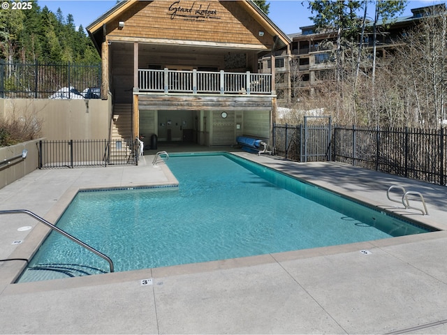 community pool with a patio area and fence