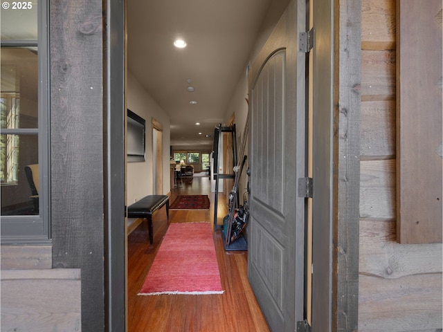 corridor featuring wood finished floors, recessed lighting, and a barn door