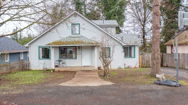 bungalow-style house featuring roof with shingles and fence