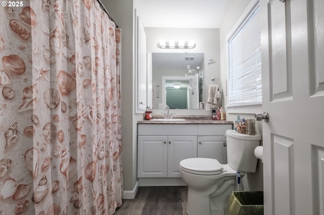 bathroom featuring curtained shower, toilet, wood finished floors, and vanity