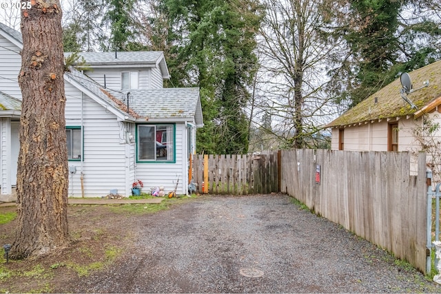 view of property exterior featuring roof with shingles and fence