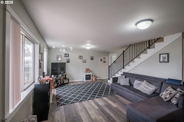 living area with dark wood finished floors, stairway, and baseboards