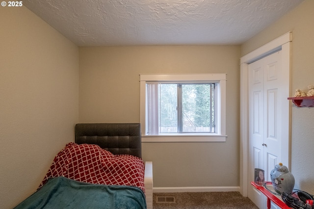 bedroom with baseboards, carpet flooring, a textured ceiling, and visible vents