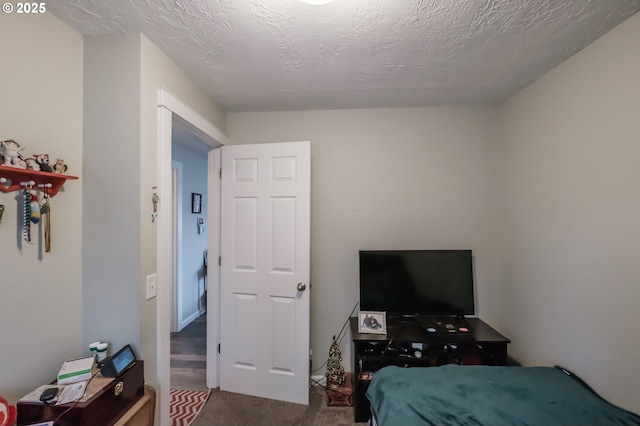 bedroom featuring dark colored carpet and a textured ceiling