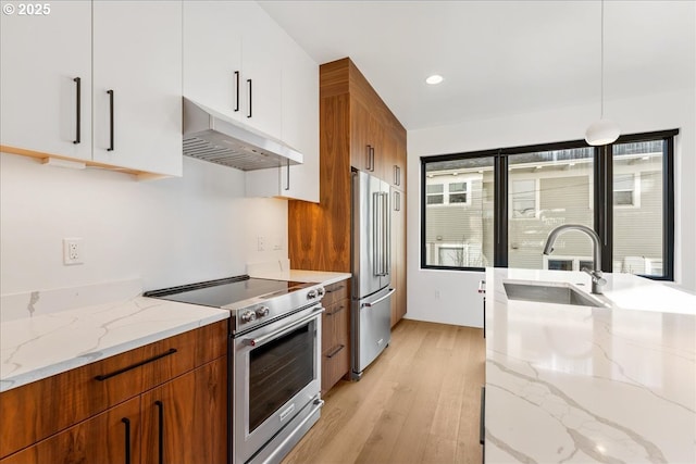 kitchen with under cabinet range hood, a sink, white cabinets, hanging light fixtures, and high end appliances