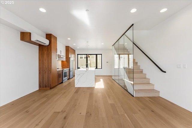 unfurnished living room with stairs, recessed lighting, light wood finished floors, and a wall mounted AC