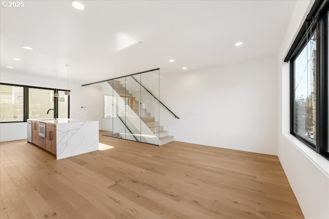 unfurnished room featuring light wood-type flooring, stairway, a sink, and recessed lighting