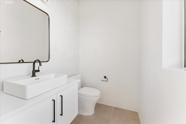 half bath with toilet, tile patterned floors, and vanity