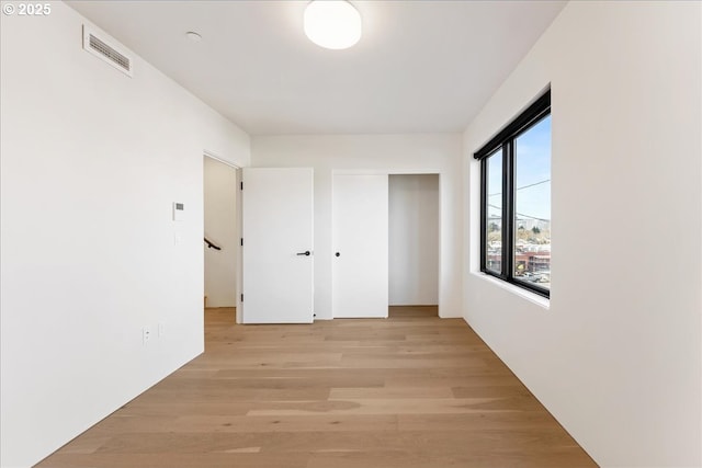 hall featuring light wood-style floors and visible vents