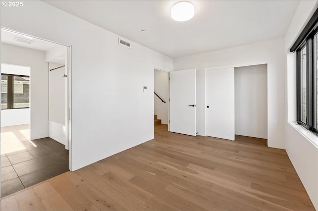 unfurnished bedroom with multiple windows, light wood-type flooring, and visible vents