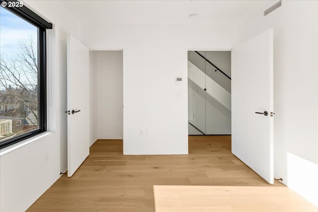 corridor featuring a healthy amount of sunlight, light wood-type flooring, and visible vents