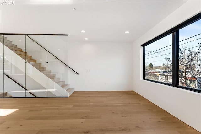 spare room featuring stairs, light wood-type flooring, and recessed lighting