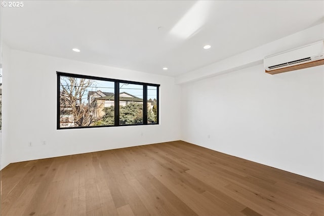 empty room featuring recessed lighting, an AC wall unit, and wood finished floors