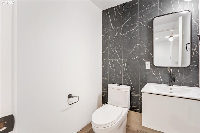 bathroom with tile walls, vanity, and toilet