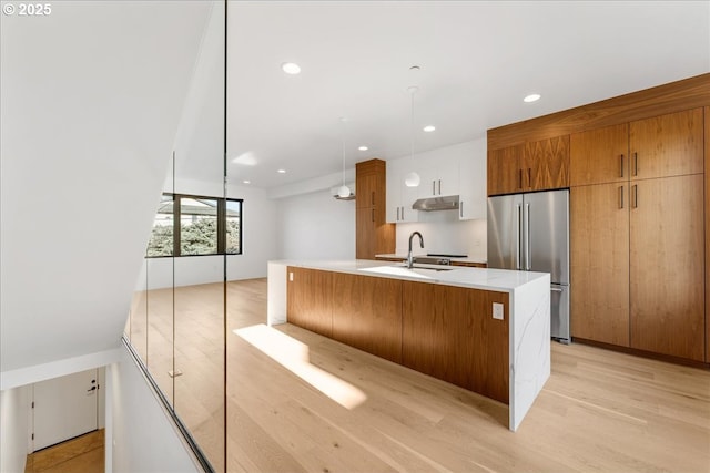 kitchen featuring a spacious island, light countertops, white cabinetry, high quality fridge, and modern cabinets