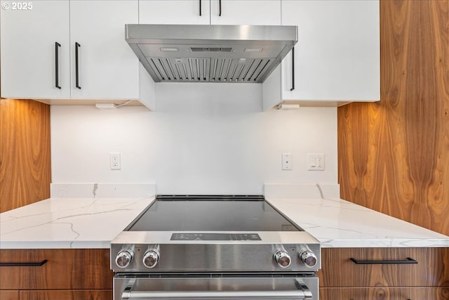 kitchen featuring light stone counters, stainless steel electric range, wall chimney exhaust hood, brown cabinetry, and modern cabinets