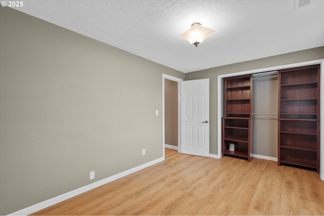 unfurnished bedroom featuring a textured ceiling, light hardwood / wood-style flooring, and a closet