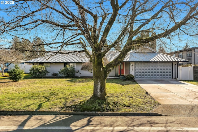 view of front facade with driveway, metal roof, an attached garage, fence, and a front yard