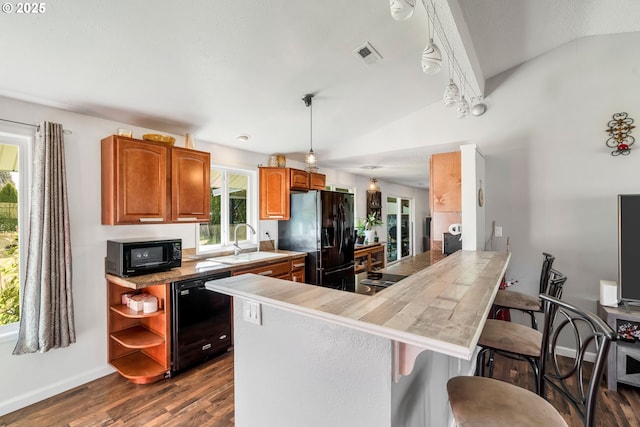 kitchen with visible vents, a kitchen breakfast bar, vaulted ceiling, black appliances, and a sink