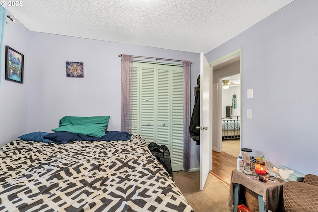 bedroom with a textured ceiling, a closet, baseboards, and light colored carpet