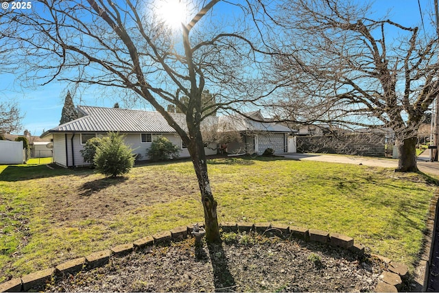 view of yard featuring concrete driveway, fence, and an attached garage