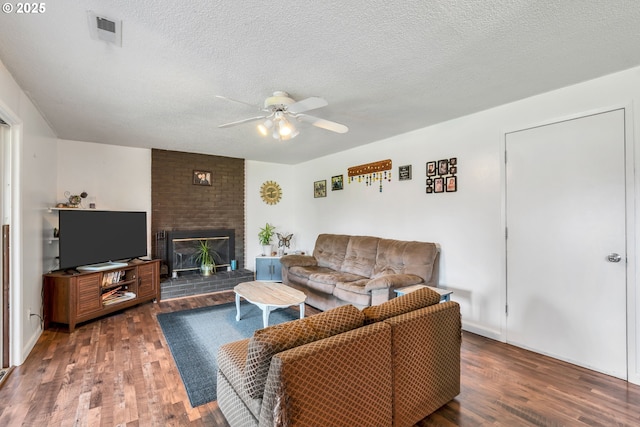 living area featuring visible vents, a fireplace, a textured ceiling, and wood finished floors