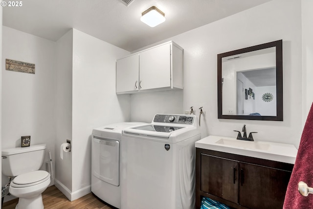 washroom with washer and clothes dryer, light wood finished floors, visible vents, a sink, and laundry area