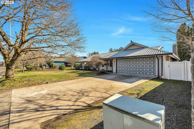 view of front of home featuring metal roof, a garage, fence, driveway, and a front lawn