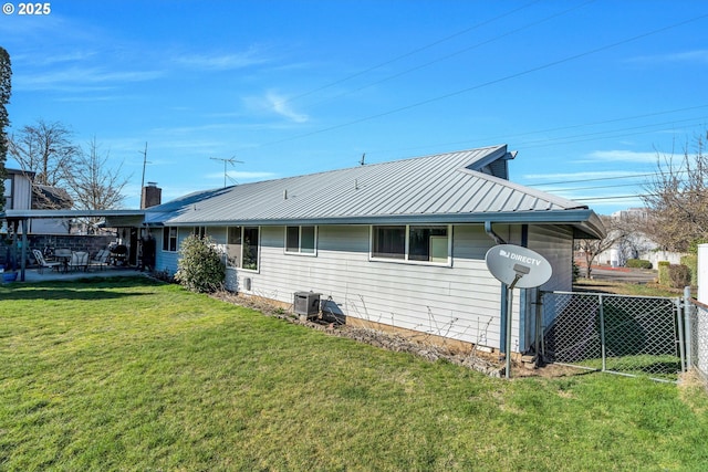 rear view of property featuring a yard, a patio, central AC, metal roof, and fence